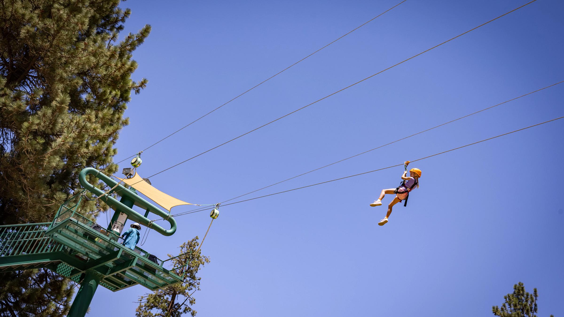 Young girl zip lining through the forest at Snow Summit