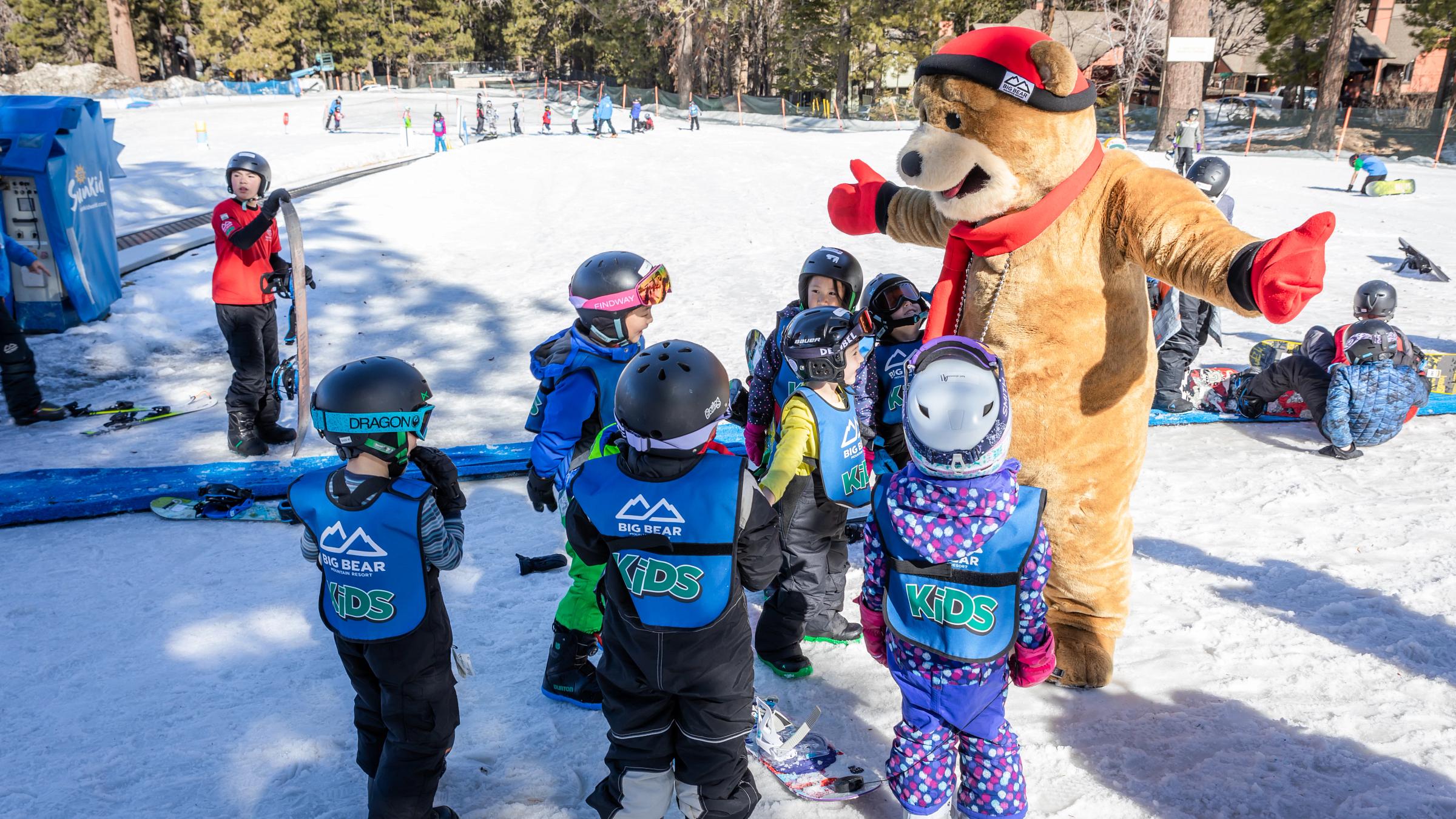 A group of kids surrounding Biggie The Bear mascot