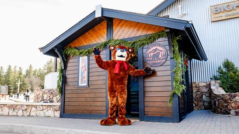 Biggie the Bear mascot standing in front of Biggie's Den in the Snow Summit base area. 