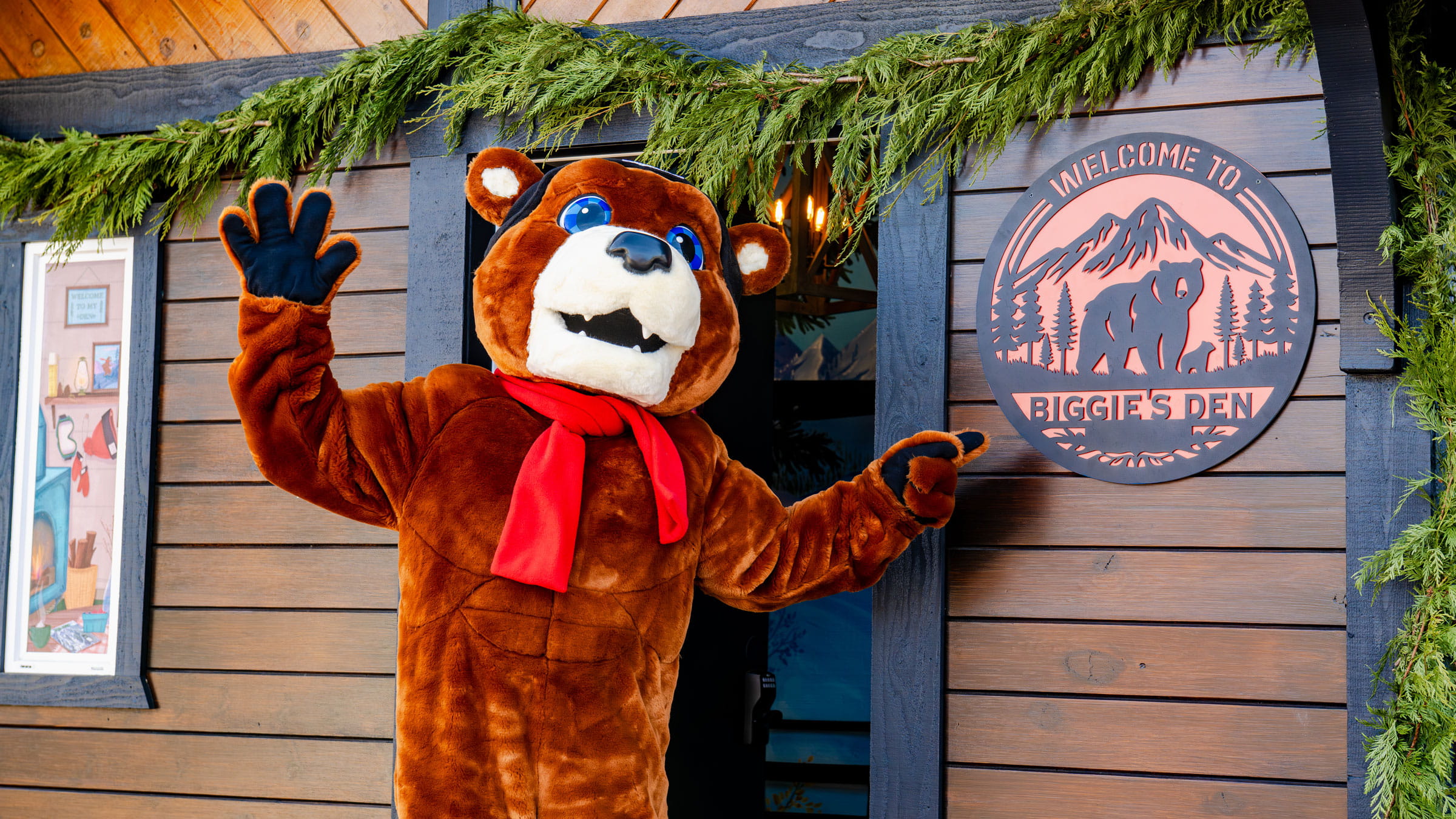 Big Bear Mountain Resort mascot, Biggie the Bear, standing in front of Snow Summit's Biggie's Den building in the base area.