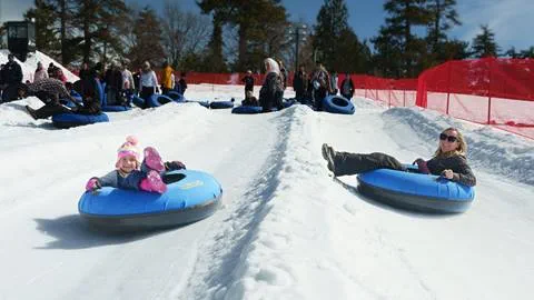 An adult and child on separate tubes and tubing lanes at Snow Valley's Coyote Creek Tube Park