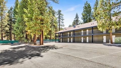 Outside view of two story employee housing building with a wide open parking lot and pine trees lining the facilities.