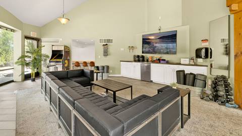 The inside area of an employee housing building that has a big lounge area with couches, coffee tables, free weights, arcade game, and coffee station.