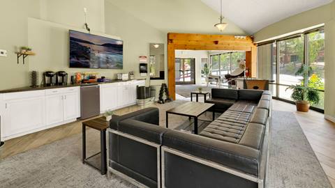 The inside area of an employee housing building that has a comfortable lounge area with couches, coffee tables, free weights, arcade games, and a coffee station.