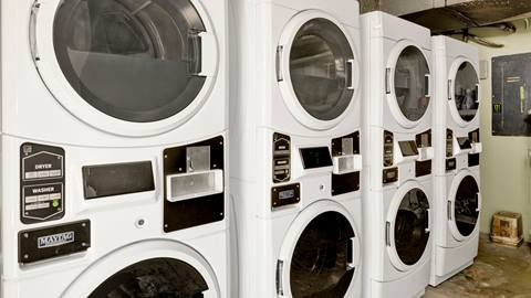 A laundry room with six washing machines and six dryers.