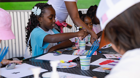 Children painting with colorful watercolors and paint brushes during an outdoor summer youth camp activity at Biggie's Adventure Outpost at Big Bear Mountain Resort.
