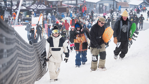 Group of snowboarders walking up the snowy mountain