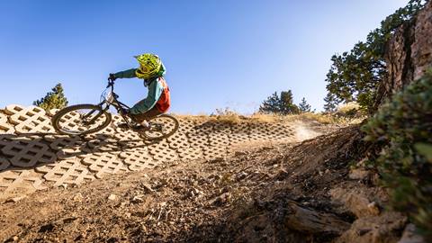 Cyclist with yellow helmet rolling through dirt and brick berm