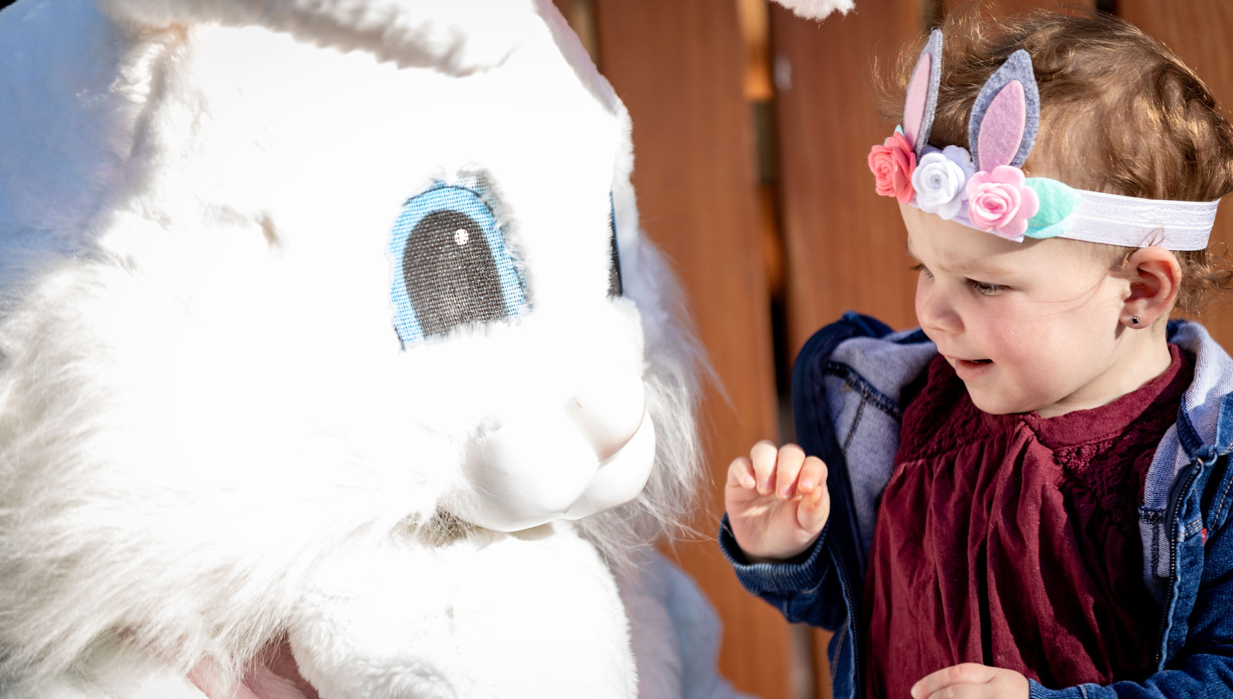 Little girl wearing a headband taking a photo with the easter bunny