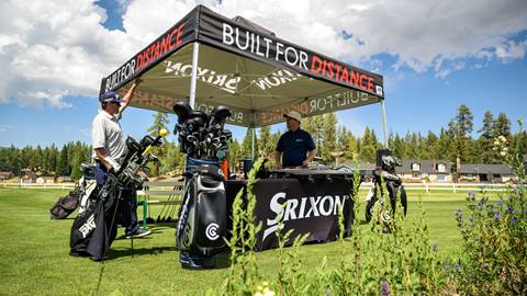 Black tent on the grass with a table and golf clubs during the Bear Mountain club demo event in the summer
