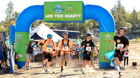 Kids sprinting out of the start/finish gate of the Kids Adventure Games.