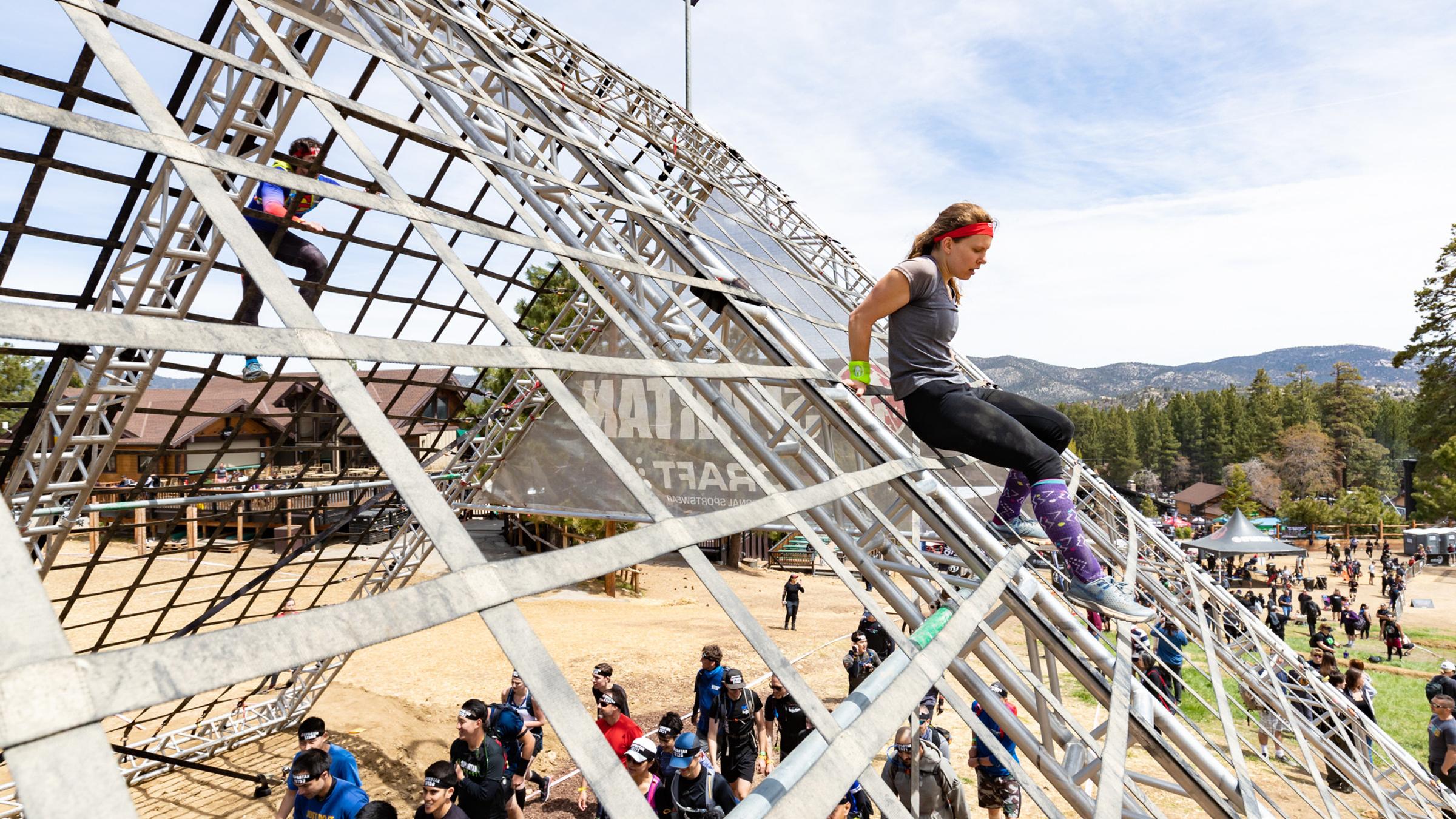Spartan race group climbing down a rail