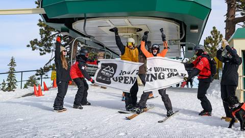 Opening Day at Snow Summit, skiers going through the first chair banner