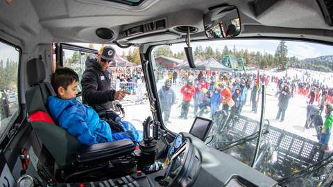 Kid in a machinery truck learning from a snow instructor