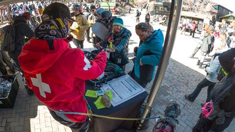 A Big Bear Mountain Resort ski patroller working a booth and educating skier and snowboarders on mountain safety during a winter event at Snow Summit.