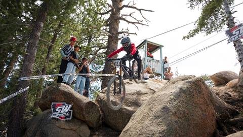 A mountain bike racer hitting the rock garden section at the Southwest Downhill event while spectators watch from the sideline.