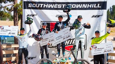 The winner podium of the Southwest Downhill mountain bike race with five teens to adults holding up their helmets and winners checks at the base of Snow Valley.