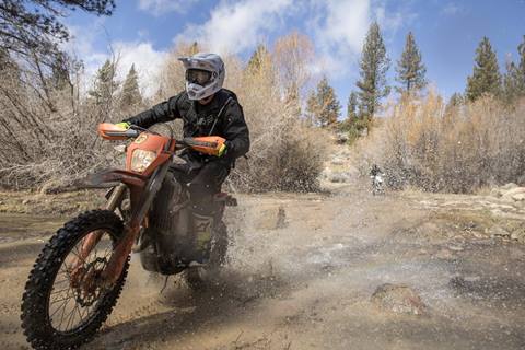 Motorcycle rider riding in mud with a big splash