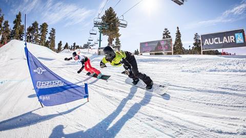 two snowboarders going head to head on a slalom race track