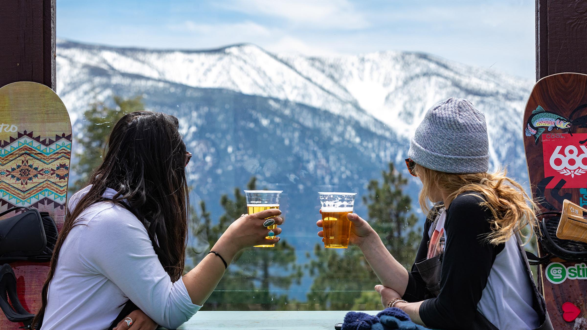 Two girls enjoying a beer with a snowy mountain view