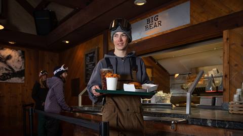 Young snowboarder carrying a plate of food