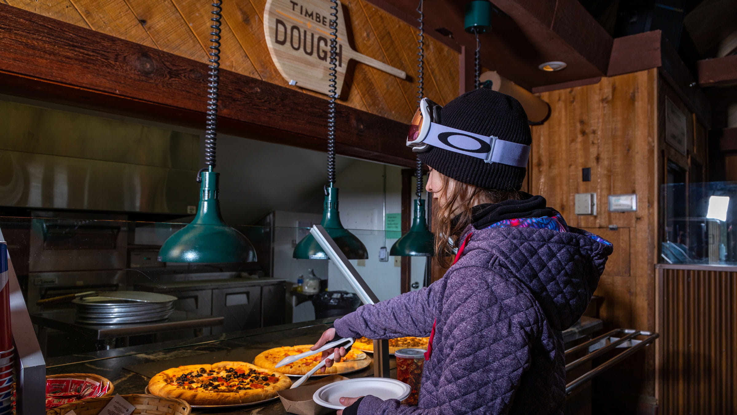 Young snowboarder grabbing a piece of pizza