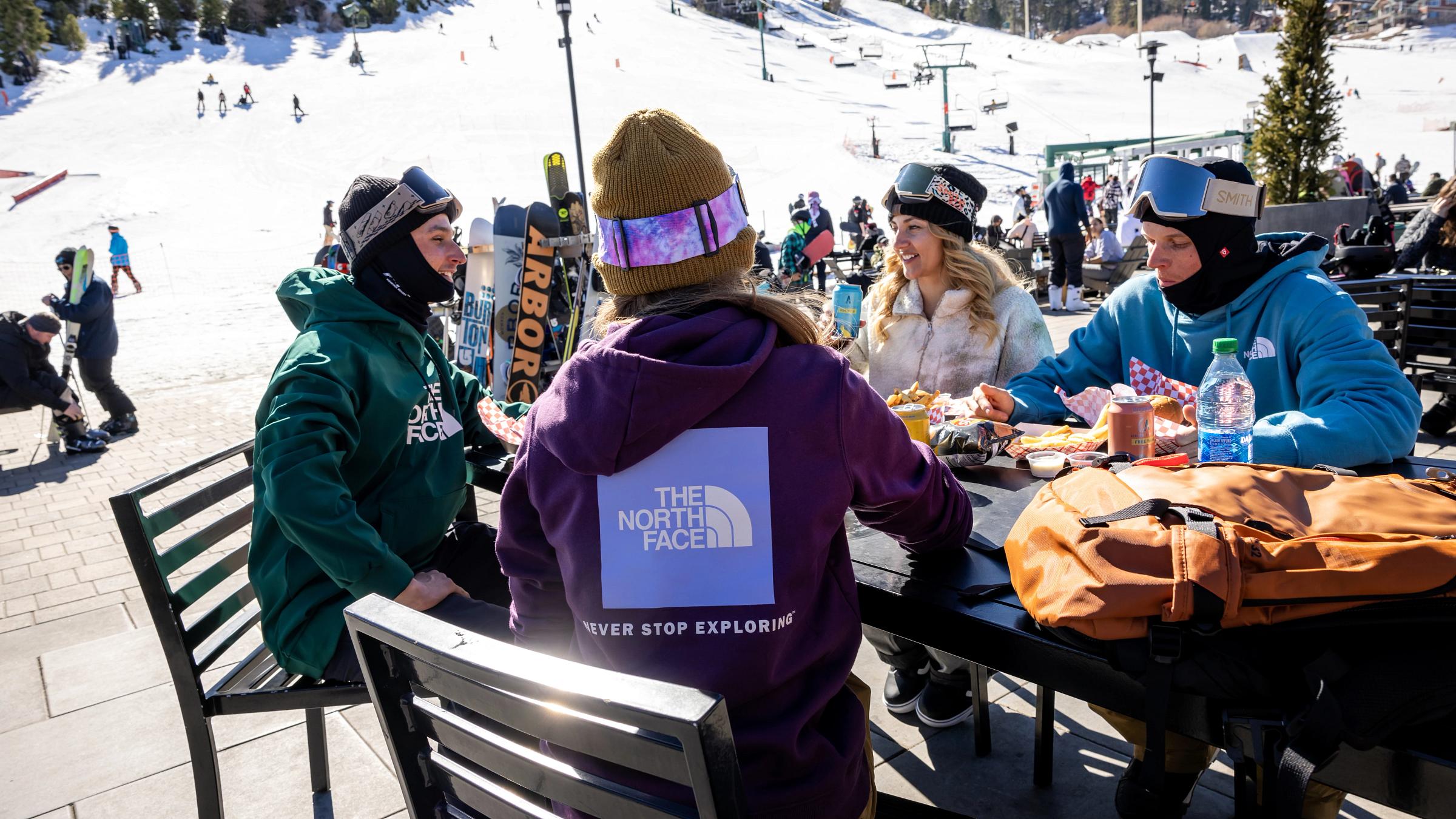 group of people sitting on a sun deck eating