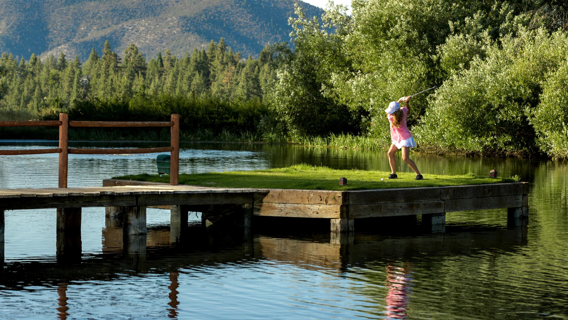 Female golfer hitting ball over the water