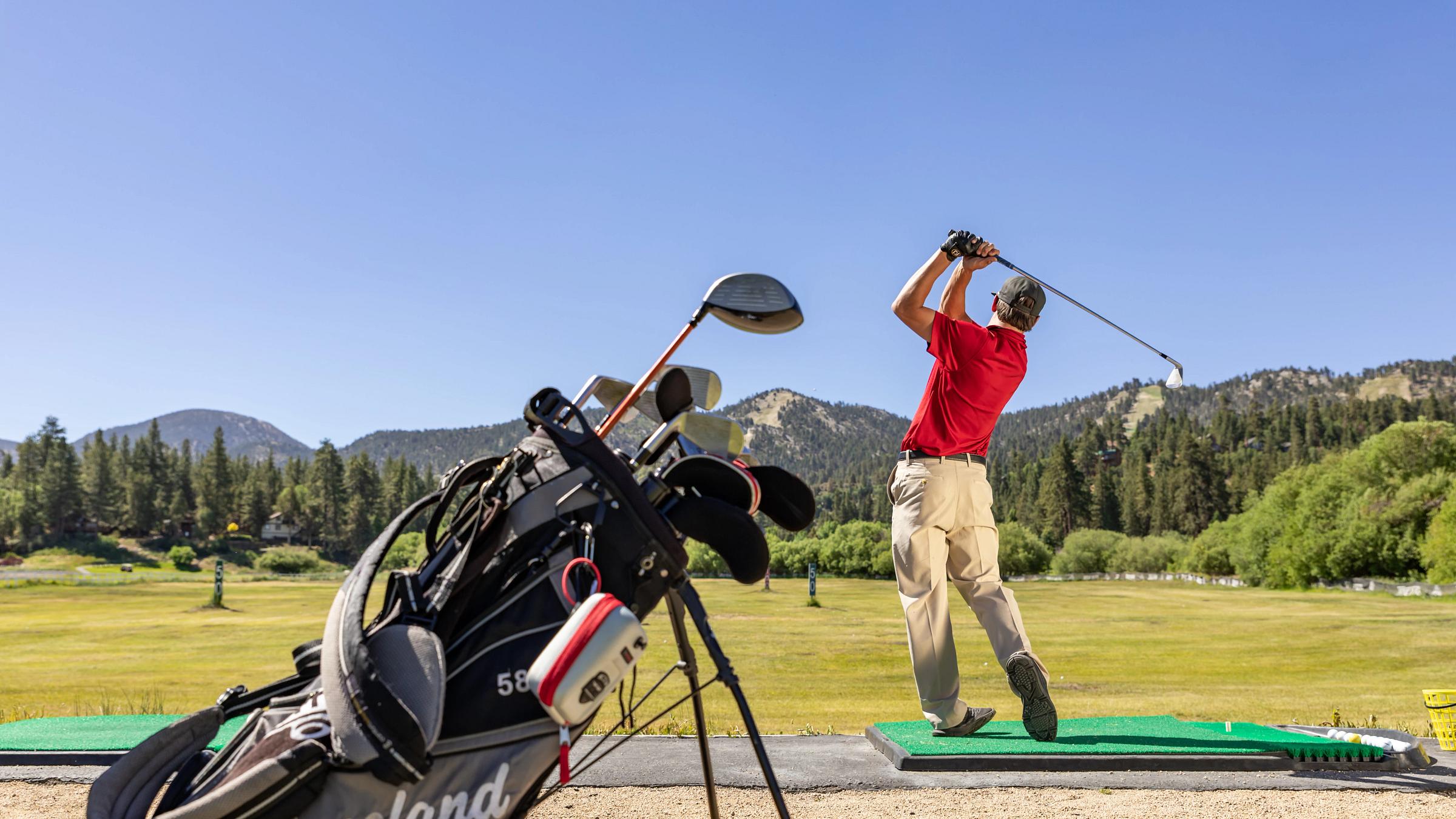 Guy in red shirt hitting a golf ball at the Bear Mountain Golf Course Driving Range