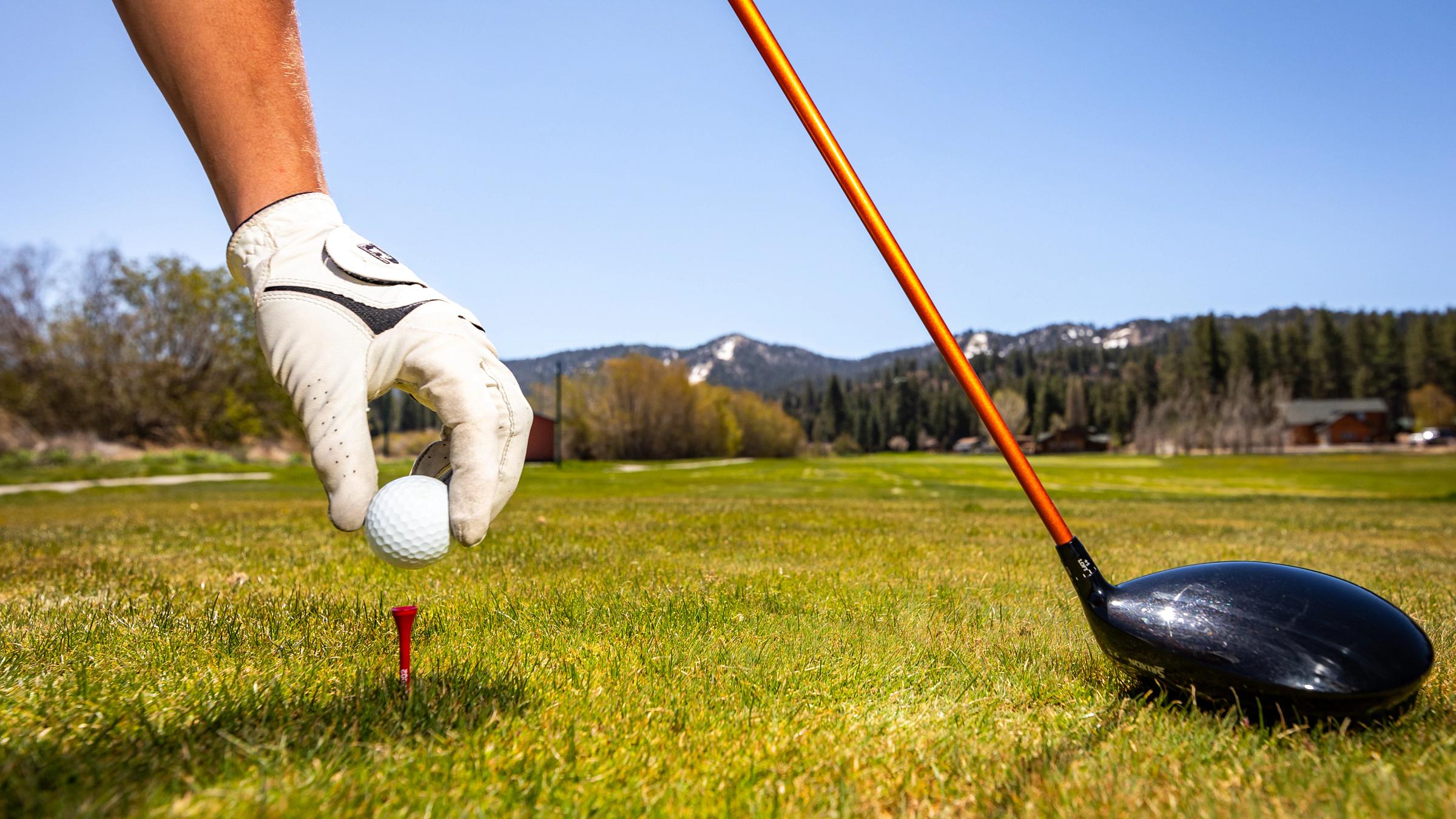 Hand wearing a golf glove putting the golf ball down
