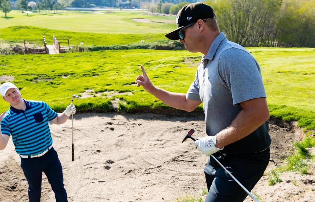 Two men golfing stuck in a sand trap