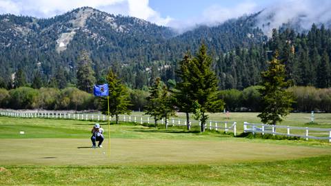  golfer crouched down near a near at thew bear mountain golf course in the summertime
