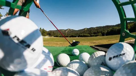 view through a bucket of golf balls with a golfer about to his the ball at the bear mountain golf course driving range