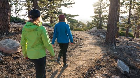 Two female hikers at snow valley in the forest on a trail