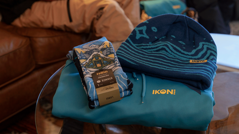 Ikon Pass sweater, socks, and beanie laid out on a table for display in the Ikon Pass Suite at Snow Summit