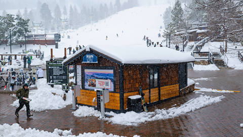 Exterior of Ikon Pass Suite building with snow in front with snowboarder walking by
