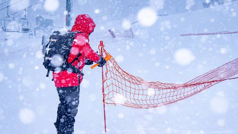 A resort employee putting fences up in the snow