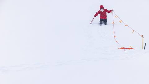 Big Bear Mountain Resort patrol team member putting up a rope zone in the snow.
