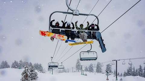 A group of Snow Valley employees, on a winter storm day, taking a snowboard ride break and heading up the chairlift.