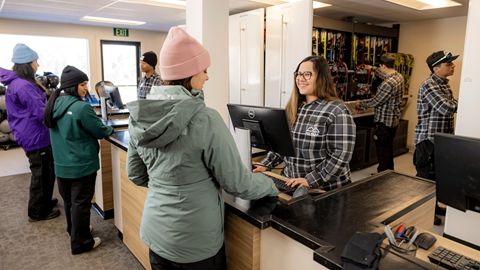 Big Bear Mountain Resort employee helping a guest checkout some skis in the rental shop