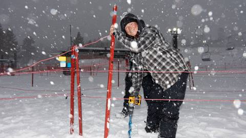 BBMR Employee drilling holes into the snow to place lift line fencing
