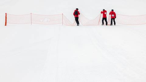 Patroller putting up orange nets on the snow to block off closed areas