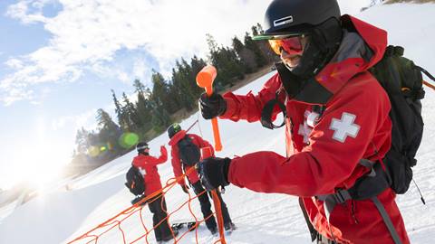 Patroller putting up orange nets in the snow