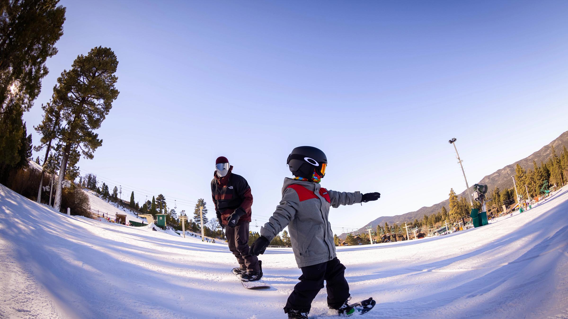 Father teaching son how to snowboard
