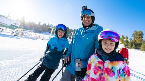 dad and two young kids going out to ski on the slopes