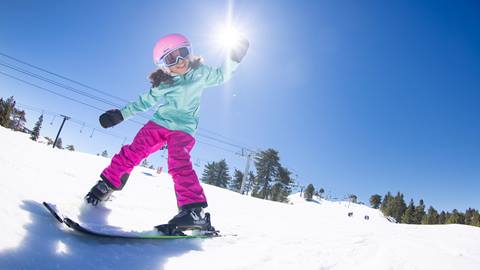 Young girl skier on the slopes, raising her left arm in the air