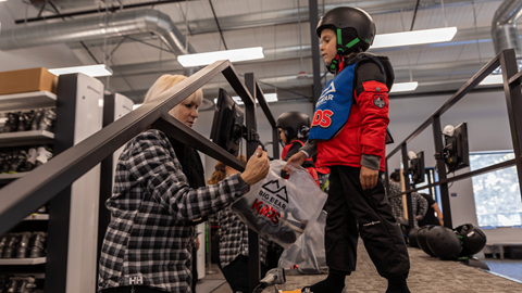 child getting fitted for snowboard equipment gear