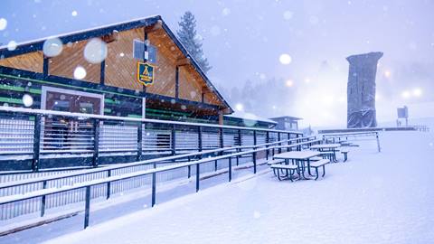 The Adventure Academy at Snow Summit during a snowstorm with fresh snow on the ground and rails surrounding the building.