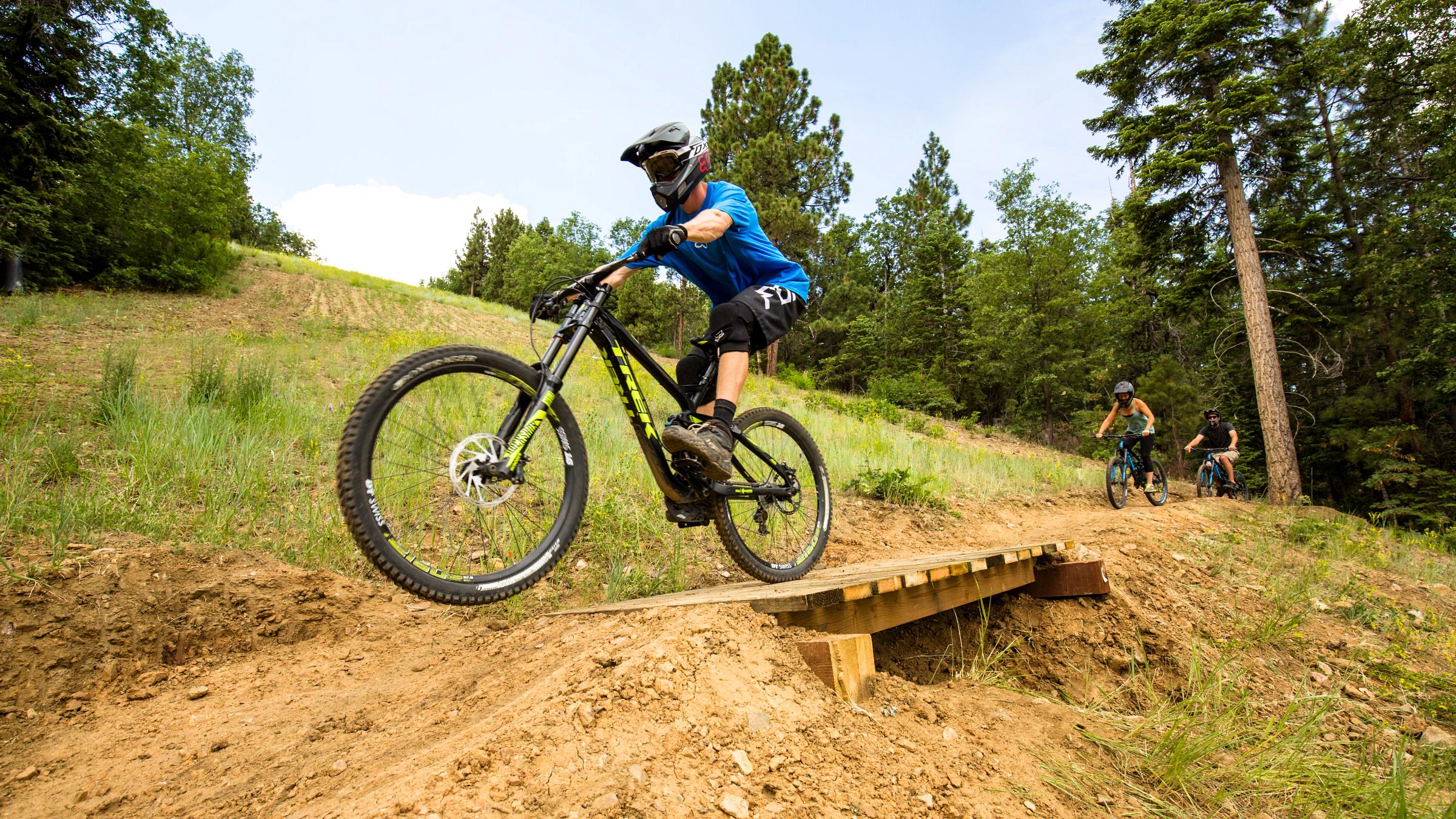 mountain biker at summit bike park going over a wooden bride feature