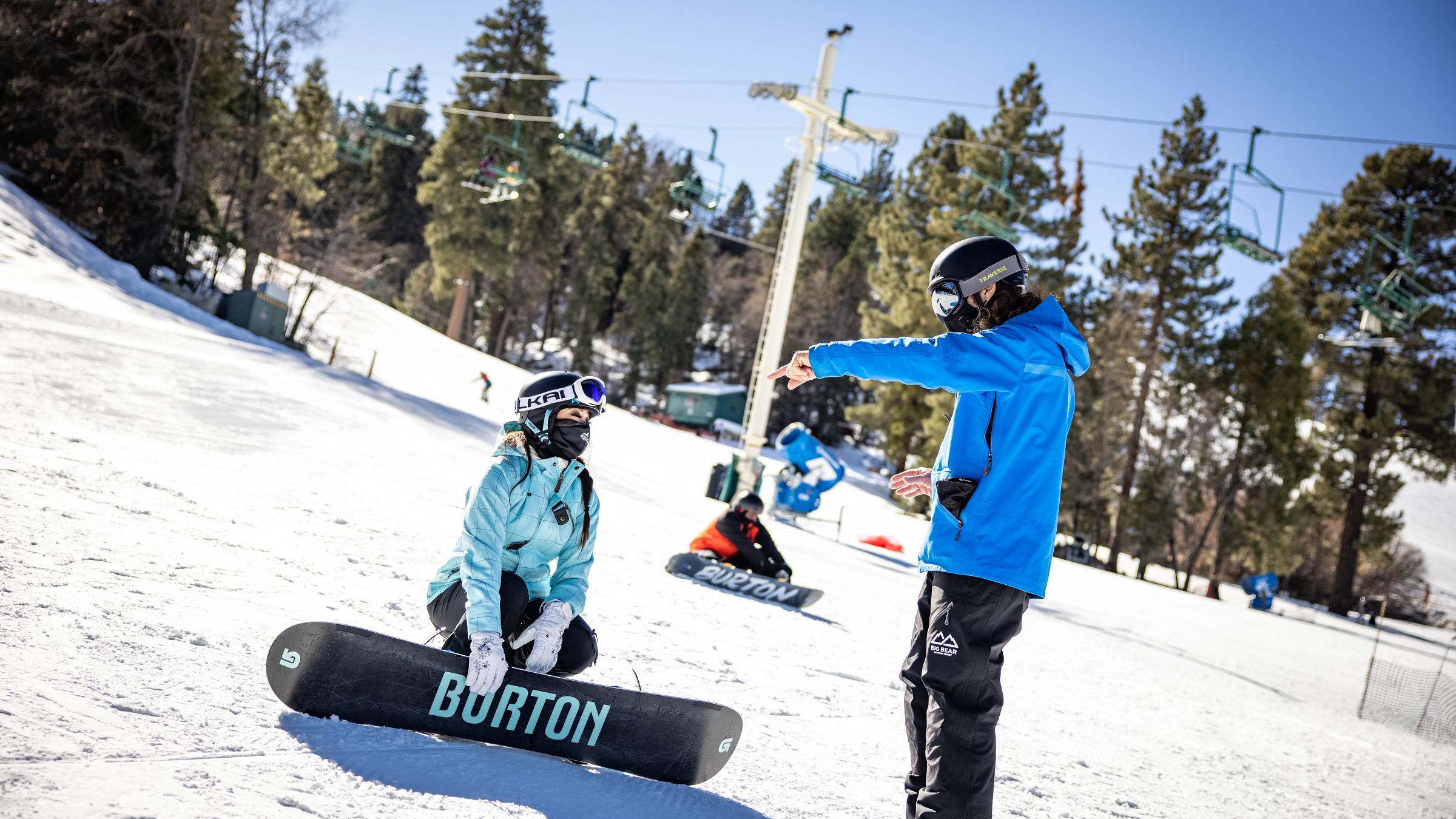 Snowboarding holding hands to instructor for balance.
